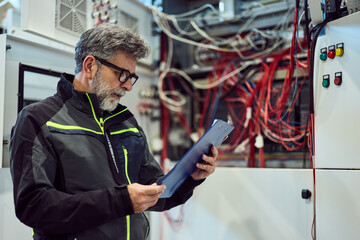 Engineer Reviewing Reports in High-Tech Electrical Facility with Industrial Equipment