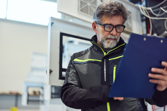 Engineer Reviewing Technical Document in Industrial Work Environment