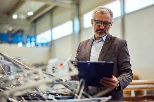 Senior Engineer Inspecting Equipment in a Modern Factory Setting for Quality Control