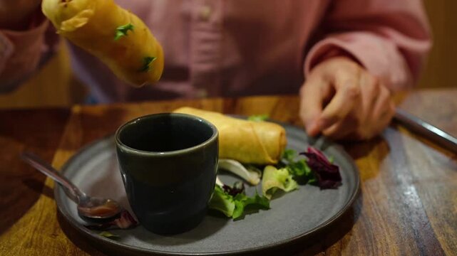 Young Asian woman eating Po Pia Tawd ( crispy Thai spring rolls stuffed with rice vermicelle and vegetables) 