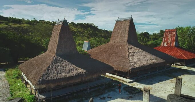Ancient megalithic tombs and traditional houses with thatched roofs stand as testaments to the rich cultural heritage of Sumba Island. Indonesia. Creating a captivating scene under the clear blue sky