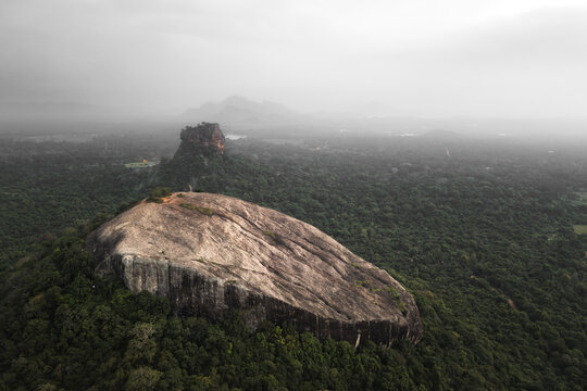 Aerial rising view visitors hiker on top viewpoint of Pidurangala Rock with Sigiriya rock view and the lush green jungle in Sri Lanka Cultural Triangle