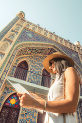 Smiling female tourist with map by colorful islamic architecture Persian-style mosque building. Travel sightseeing planning, cultural discovery, solo journey, heritage adventure