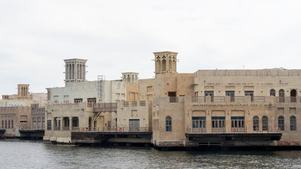Fototapeta premium Street of Dubai old city or town or old village Al Seef Khor in Al Fahidi neighborhood, United Arab Emirates. Waterfront promenade along bank of Dubai Creek
