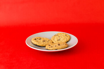 Three chocolate chip cookies on a white plate