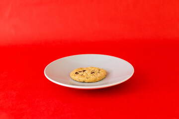 A cookie is on a plate on a red background