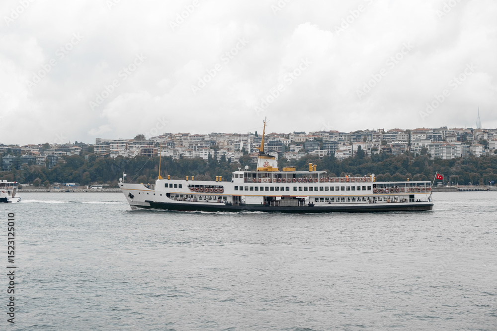 Aufkleber ferry crossing the bosphorus strait with city skyline in background on a cloudy day