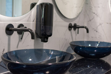 Two sinks in a bathroom with a mirror above them. The sinks are blue and the mirror is white with LED light.