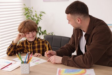 Man teaching kid to draw at painting lesson indoors
