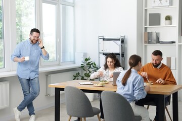Colleagues eating and chatting during lunch break in office