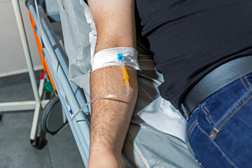 A man arm with an IV drip. An IV catheter in a man's arm. Intravenous administration of drugs using an infusion system.