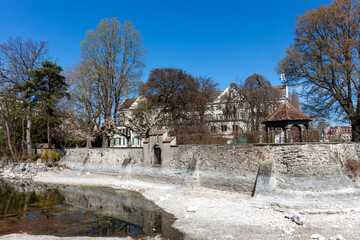A tranquil scene along the shores of Lake Constance features a historic stone retaining wall...