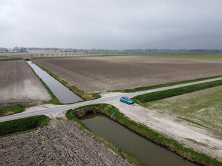 Rural landscape with farmland and a parked vehicle under overcast sky in a tranquil countryside...