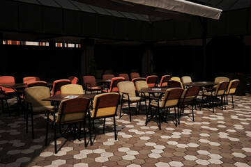 Empty colorful outdoor cafe chairs arranged on a patterned pavement in Serbia.