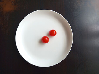 Cherry tomatoes lie in a white plate on the table