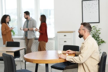 Fototapeta premium Man eating lunch at table. Colleagues having break in office