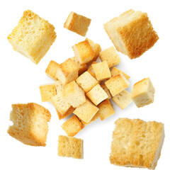 Delicious crispy croutons falling onto pile on white background, top view