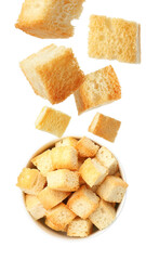 Delicious crispy croutons falling into bowl on white background, top view