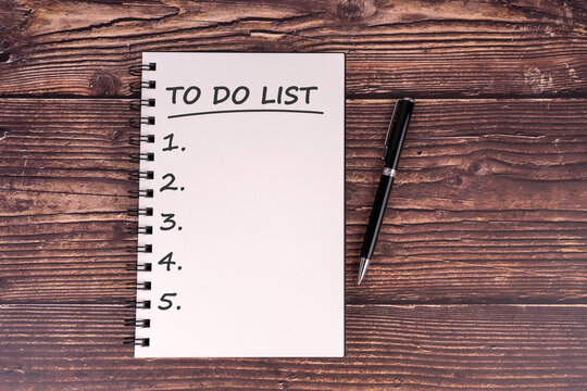 Top view of a blank to-do list in a spiral notebook with a pen on rustic wooden table. Perfect for productivity, planning, organization, or motivational themes.

