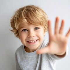 smiling child boy waving hand eye contact with camera indoor studio light clean background portrait orientation