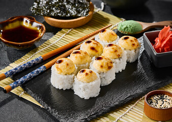 Baked sushi roll with cheese cream topping on black slate, vibrant lighting, high‑contrast modern food styling
