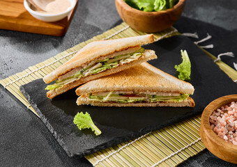 Chicken sandwich on slate plate, bright natural lighting, minimalistic composition