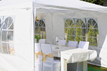 Garden tent for a communion party with a table and white decorations.