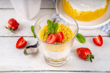 Classic cheesecake in glass, with fresh strawberry and golden cookie crumble
