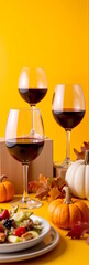 Elegant red wine glasses with rich dark wine set against a vibrant yellow background, accompanied by seasonal pumpkins and a fresh salad, autumn celebration concept of restaurants or catering