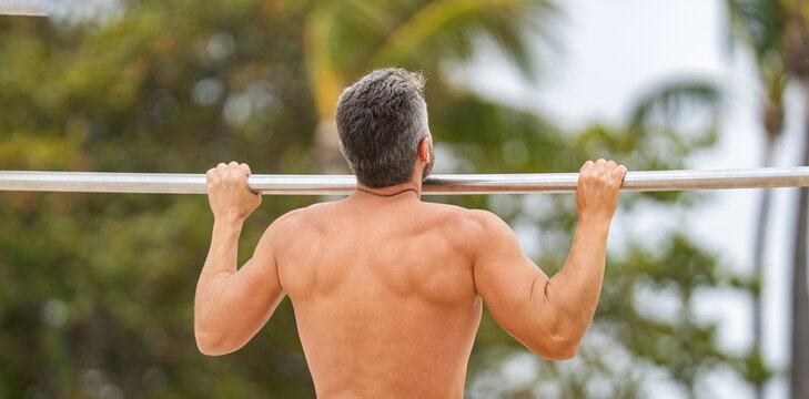 Man muscular back athlete doing pull up in outdoor gym. Sport lifestyle. Muscular biceps and triceps. Strong athlete. Man pullup. Muscular man sportsman with strong back muscle. Sport pullup workout - Powered by Adobe