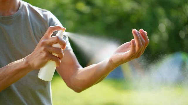 Man spraying mosquito and tick repellent on arm outdoors during summer for insect protection