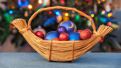 Wiklinowy koszyk w kształcie łódki wypełniony bańkami, w tle choinka z lampkami, © PIOTR D