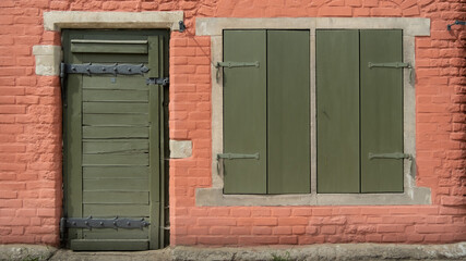Zielone drzwi i okno z drewnianymi okiennicami 