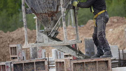 Pouring a concrete foundation at the construction site using a crane and concrete mixer