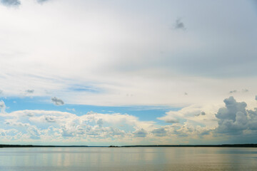 Grey rainy clouds over the lake. Dense forest along the lake shore during a storm.