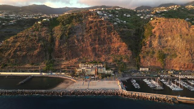 Aerial panoramic view of the coastal town of Calheta on high cliffs, marina and beaches on the waterfront. Madeira, Portugal.
