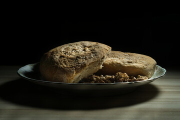 Two loaves of homemade bread with sesame seeds are placed on a plate with walnuts, creating a rustic, wholesome image