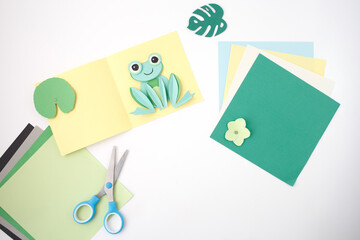 Pop-up paper frog in handmade card for kids DIY tutorial, preschool activity, stationery promotion, art class material, greeting card brand, or home education platform visual,