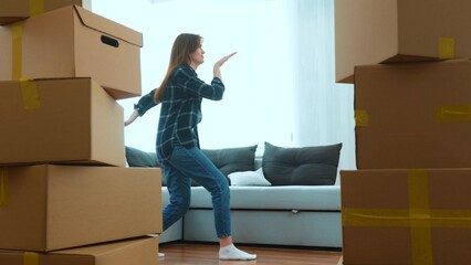Happy positive couple of man and woman having fun dancing in room in new home with many boxes. Caucasian young wife and husband doing funny dance in new apartment. Moving in together