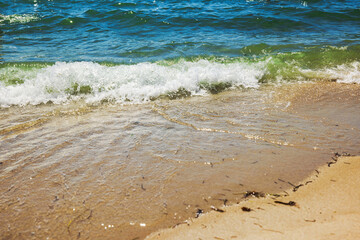 Close up view of small wave rolling onto golden sand at Miami Beach in bright sunlight.