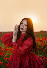 Sexy girl in short red dress posing on poppy field of flowers.
