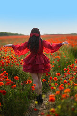 Sexy girl in short red dress posing on poppy field of flowers.