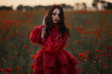 Sexy girl in short red dress posing on poppy field of flowers.