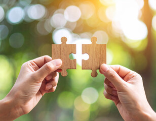 Connecting two wooden puzzle pieces, hands clasped together, symbolizes teamwork and collaboration in serene outdoor setting. warm sunlight creates joyful atmosphere