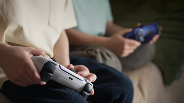 Young boys presses buttons, using joypad controller, wireless gamepad. Hobby.