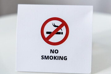 No smoking sign on white table. Red and white paper sign with cigarette symbol and crossed-out circle.