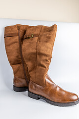 Close-up of brown knee-high boots featuring a mix of leather and suede with rugged soles