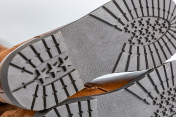 Detailed view of brown boots with rugged black soles and deep traction pattern. High-quality and comfortable footwear