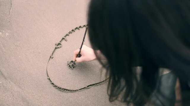 A Japanese woman from back view drawing cute smiling face on the beach, Kagawa Prefecture in Japan, Travel or outdoor
