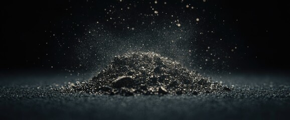 Dark gritty pile with particles suspended against a black backdrop, subtle gradients of light